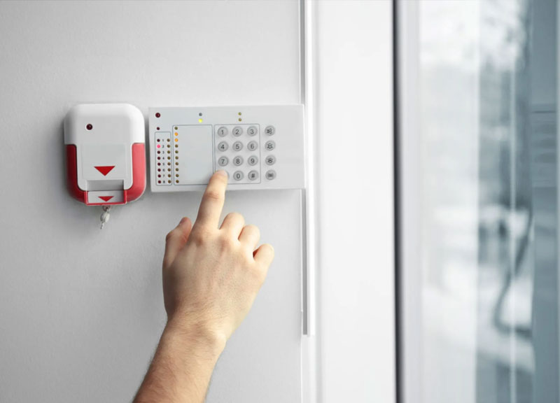 Young woman entering code on keypad of home security alarm