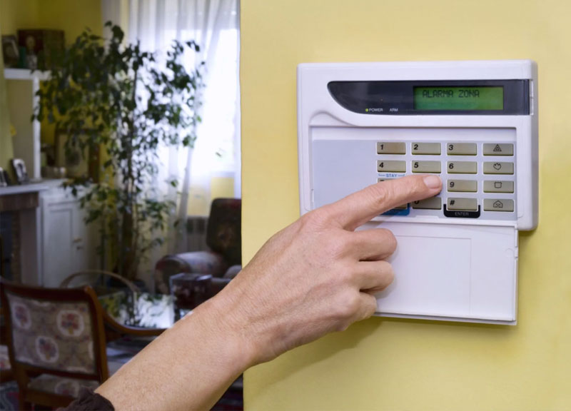 Young woman entering code on keypad of home security alarm